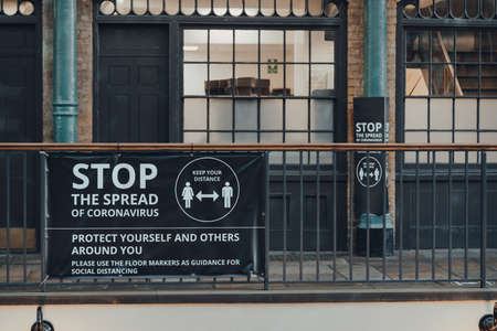 London, UK - November 19, 2020: `stop the spread Coronavirus warning sign in Covent Garden Market, one of the most popular tourist sites in London, UK. Selective focus.のeditorial素材