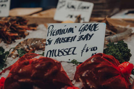 Close up of price tag on premium grade St Austell Bay mussels on sale at a market in London, UK,...