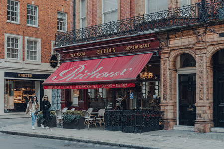 London, UK - December 5, 2020: Facade of Richoux tea room and restaurant in Mayfair, an affluent area in the West End of London, women walk past, motion blur.のeditorial素材