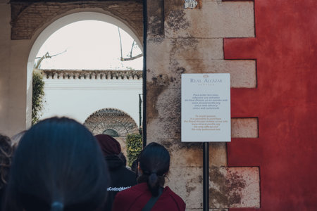 Seville, Spain - January 19, 2020: Sign on Puerta del Leon gate in Alcazar of Seville, a royal palace built for the Christian king Peter of Castile, people queue to enter, selective focus.のeditorial素材