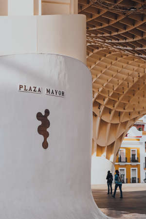 Seville, Spain - January 19, 2020: Plaza Mayor signs at the base of Metropol Parasol, the largest wooden structure in the world, in Seville. Selective focus, people walk on background.のeditorial素材