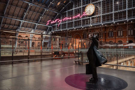 London, UK - August 16, 2019: Side view of a statue of John Betjeman by Martin Jennings within interior of St. Pancras Station, one of the largest railway stations in London, and a home to Eurostar.のeditorial素材