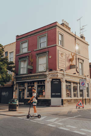 London, UK - August 12, 2020: Facade of the closed Bucks Head pub on High Street in Camden Town, London, an area famed for its market and nightlife, man on electric scooter rides past, motion blur.のeditorial素材
