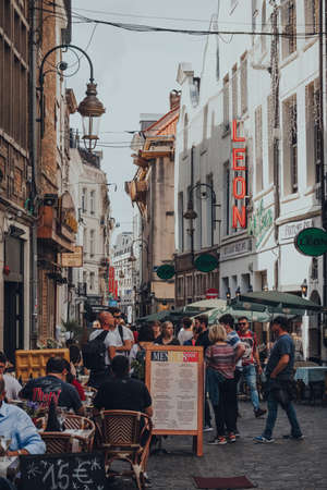 Brussels, Belgium - August 16, 2019: People walking past the restaurants on a narrow street in...