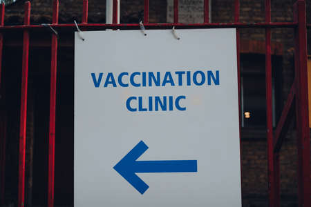 Directional sign to Vaccination Clinic on a street in London, UK.の写真素材