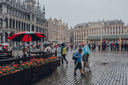 Brussels, Belgium - August 17, 2019: People walking on Grand Place, the central square of Brussels surrounded by opulent guildhalls, the city's Town Hall and City Museum, in the rain.のeditorial素材