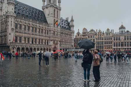 Brussels, Belgium - August 17, 2019: View of the tourists on Grand Place, the central square of Brussels surrounded by opulent guildhalls, the city's Town Hall and City Museum, in the rain.のeditorial素材