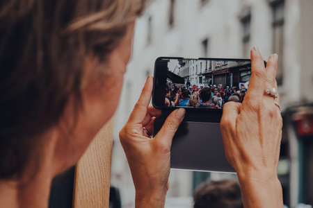 Brussels, Belgium - August 17, 2019: Woman taking video of a band performing on a street in old town...
