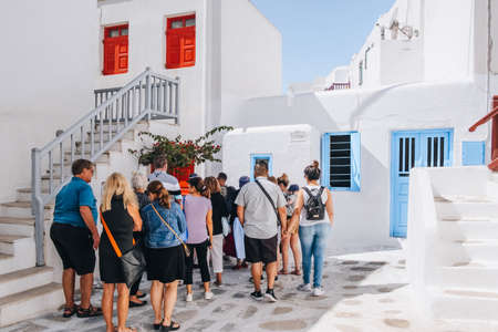 Mykonos Town, Greece - September 23, 2019: Group of tourists walking past whitewashed buildings on a street in Hora (also known as Mykonos Town), the islands well-preserved port and capital.のeditorial素材