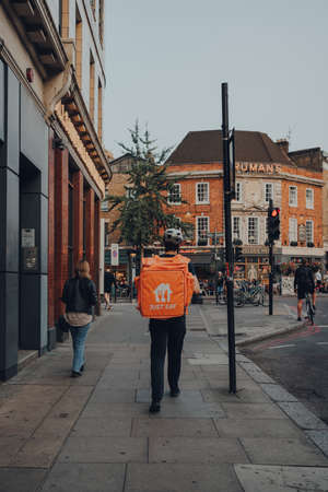 London, UK - September 03, 2021: Just Eat delivery driver delivering on a street in East London. Just Eat is a company that enables food to be delivered from restaurants that do not offer delivery.のeditorial素材