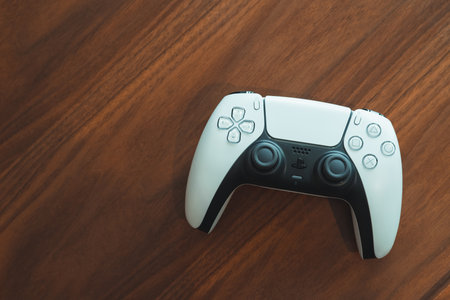 London, UK - May 25, 2021: Playstation 5 (PS5) controller on a wooden table. Playstation 5 is the latest video game console from Sony released in November 2020 as a successor to the PlayStation 4.のeditorial素材