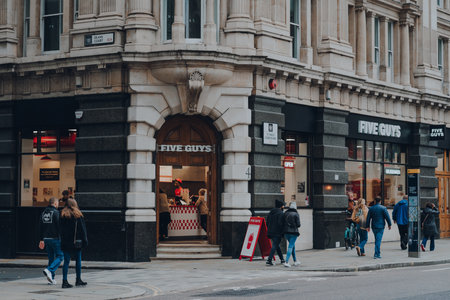 London, UK - October 23, 2021: Exterior of Five Guys, an American fast casual restaurant chain offering over 250000 possible ways to order a burger, in City of London, people walking past.のeditorial素材