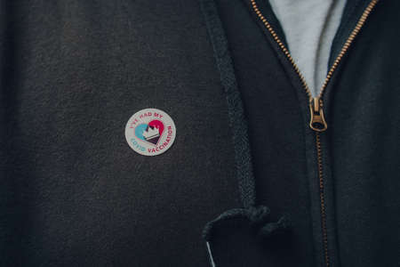 London, UK - December 17, 2021: NHS Vaccination programme I've Had My Covid Vaccine sticker on a chest of a black hoodie, received after successful Covid-19 vaccination, selective focus.のeditorial素材