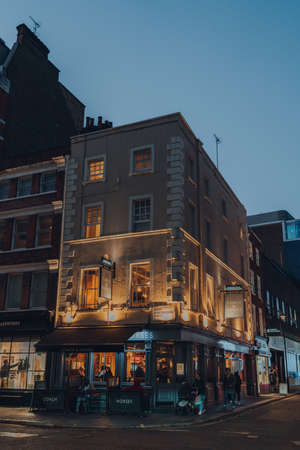London, UK - November 23, 2021: Illuminated exterior of Coach and Horses, a traditional corner pub in 18th-century building in Soho, an area of London with lots of cafes and restaurants.のeditorial素材