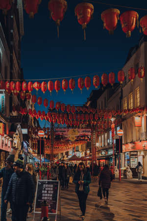 London, UK - November 23, 2021: People walking under Chinese lanterns on the street in Chinatown, London. Chinatown is home to a large East Asian community and is famous for its eateries and events.のeditorial素材