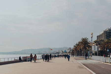 Nice, France - March 10, 2022: People walking on The Promenade des Anglais in Nice, a famous tourist destination on the French Riviera, on a sunny spring day.のeditorial素材