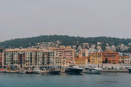 Nice, France - March 11, 2022: Yachts moored in front of the pastel coloured buildings in the harbour in Nice, a famous tourist destination on the French Riviera.のeditorial素材