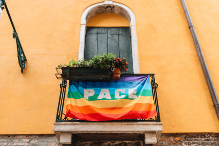 Rainbow flag with a word Pace (Peace) handing on balcony railings of a building in Venice, Italy.の写真素材