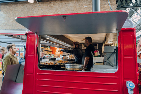 London, UK - February 02, 2023: Staff working at an Indian street food inside Spitalfields Market, one of the finest Victorian Markets in London with stalls offering fashion and food.のeditorial素材
