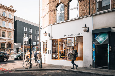 London, UK - February 09, 2023: Exterior of Bao Noodle Shop in Spitalfields, a trendy area of Londons East End that is home to an array of markets, bars and restaurants, people walking past.のeditorial素材