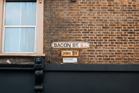 London, UK - February 09, 2023: English and Bengali bilingual street name sign on a building in Bacon Street near Brick Lane, the heart of the Londons Bangladeshi-Sylheti community.のeditorial素材