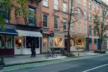 New York, USA - November 221, 2022: Row of shops on a street in West Village, a charming area of Manhattan famous for its shops and restaurants, man walking past.のeditorial素材