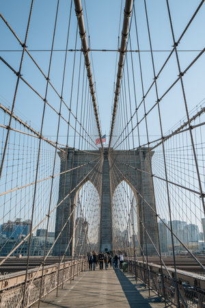 New York, USA - November 21, 2022: People walking on Brooklyn Bridge, a famous hybrid cable-stayed-suspension bridge in New York City, on a sunny winter day.のeditorial素材