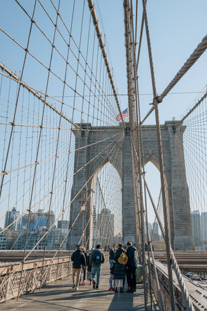 New York, USA - November 21, 2022: People walking on Brooklyn Bridge, a famous hybrid cable-stayed-suspension bridge in New York City, on a sunny winter day.のeditorial素材