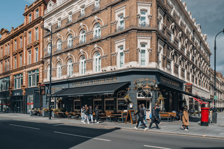 London, UK - April 13, 2023: People walking on a street in front of The Jack Horner, a traditional Victorian oak-panelled pub on Tottenham Court Road.のeditorial素材