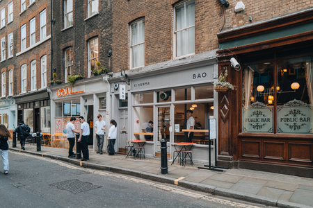 London, UK - April 13, 2023: Staff smoking outside Bao Taiwanese restaurant in Soho, an area of London famous for LGBTQ+ bars, restaurants and clubs.のeditorial素材