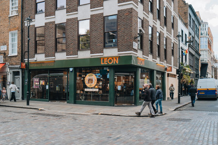 London, UK - April 13, 2023: Leon restaurant on Broadwick Street, London. Leon is a fast food chain based in the United Kingdom, established in 2004 with around 70 outlets in 2021. People walk past.のeditorial素材