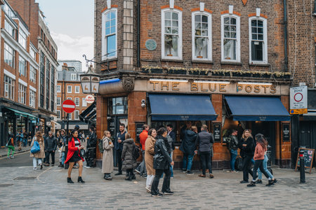 London, UK - April 13, 2023: People walking past The Blue Posts pub in Soho, an area of London famous for LGBTQ+ bars, restaurants and clubs.のeditorial素材
