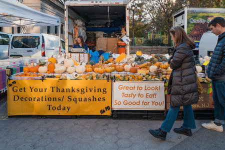 November 23, 2022 - New York, USA: Pumpkins and squashes at Grow NYC Union Square Greenmarket, a year-round farmers market with various farm and small batch food producers, people walk past.のeditorial素材
