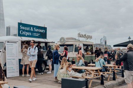 London, UK - July 06, 2023: People enjoying food from food trucks on Thames riverside by Tower of London, one of London's top tourist attractions.のeditorial素材