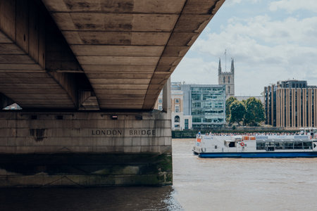 London, UK - July 06, 2023: City cruise boat passing London Bridge on the River Thames. River cruises are very popular with tourists all year around.のeditorial素材