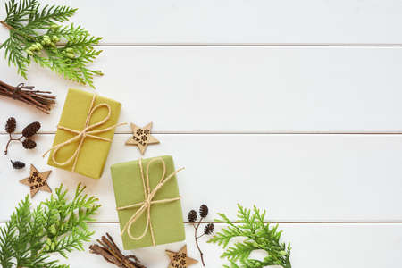 Christmas or New Year arrangement. Corner border made of gift boxes, conifer branches and natural decorations on white wooden background. Flat lay, top view, copy space.の写真素材