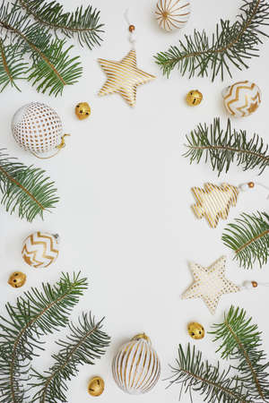 Christmas or New Year composition. Frame made of fir tree branches and golden decorations on white background. Flat lay, top view, copy space.の写真素材