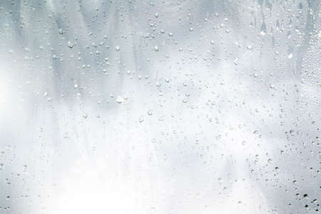 Natural pattern. Raindrops on window glasses surface with cloudy background.