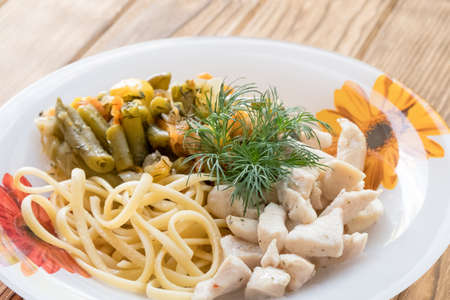 Chicken meat in a plate with fried vegetables and pastaの写真素材