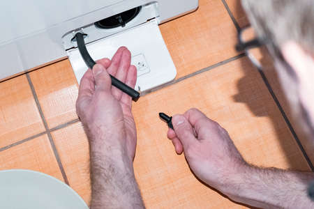 The master carries out the maintenance of the washing machine, cleaning the filterの写真素材