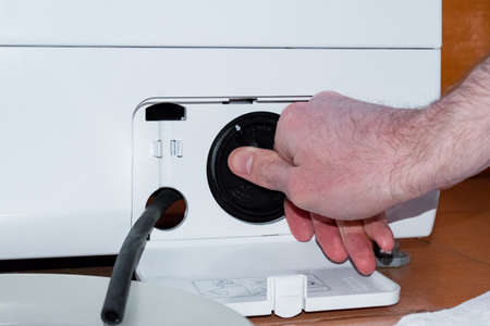 Open cover of washing machine filter. Repair work of the washing machineの写真素材