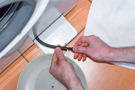 The master carries out the maintenance of the washing machine, cleaning the filterの写真素材