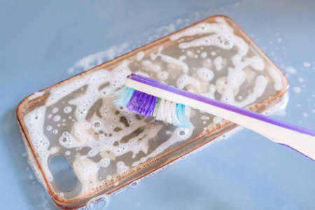 Cleaning the silicone phone case with toothbrush, foam and soap