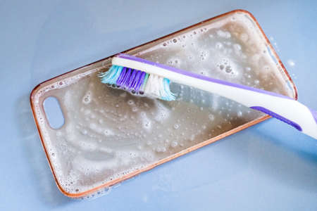 Cleaning the silicone phone case with toothbrush, foam and soapの写真素材