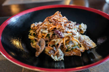 Hearty salad of vegetables, meat, mushrooms with sauce. Dish on a dark plate.の写真素材