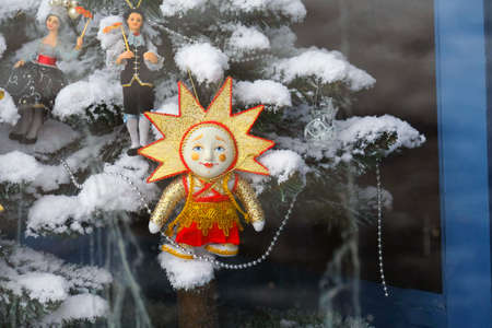 Christmas tree toy in shop window. The sun with a face. Dirty windows.のeditorial素材