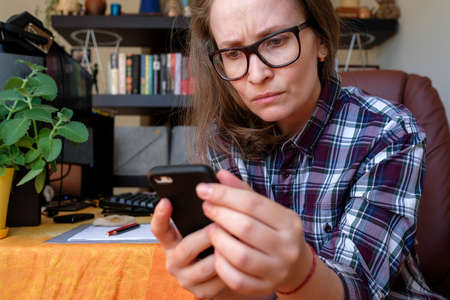 A woman is reading bad information from a gadget. Negative emotions. Stay home
