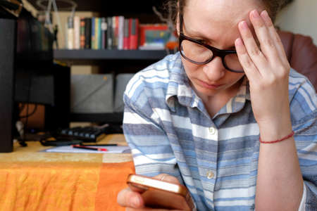 Reads bad news from the phone. A young woman is holding on to her head. Negative onlineの写真素材