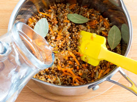 Add water to the pan with buckwheat and vegetables. Cook cereal with vegetablesの写真素材