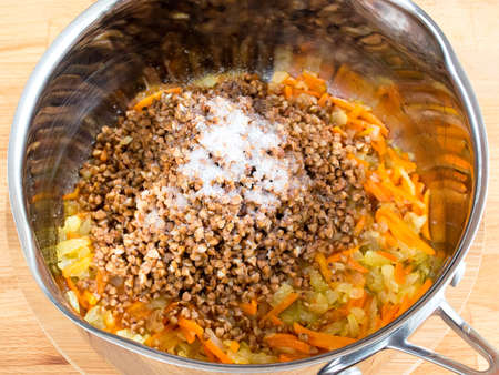 Buckwheat with carrots and onions in a bucket. Cook buckwheat with vegetables and seasonings. Cooking for vegansの写真素材